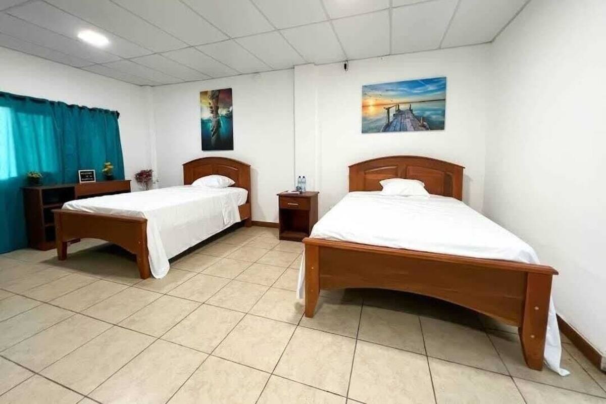 A hotel room with two wooden beds, a desk, and a chair.