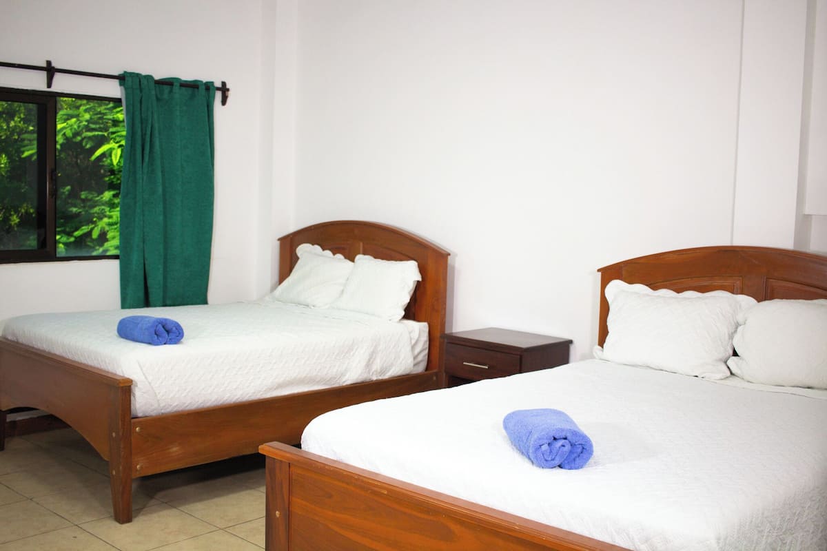 Two single beds with wooden headboards, white bedding, and green curtains.
