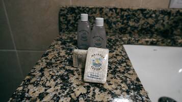 A bathroom counter with three bottles of Majahual Resort shampoo and a bar of shampoo.