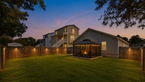 A residential backyard with a covered patio area, a wooden fence, and a well-maintained lawn. - Private home along New River NC (Sneads Ferry)