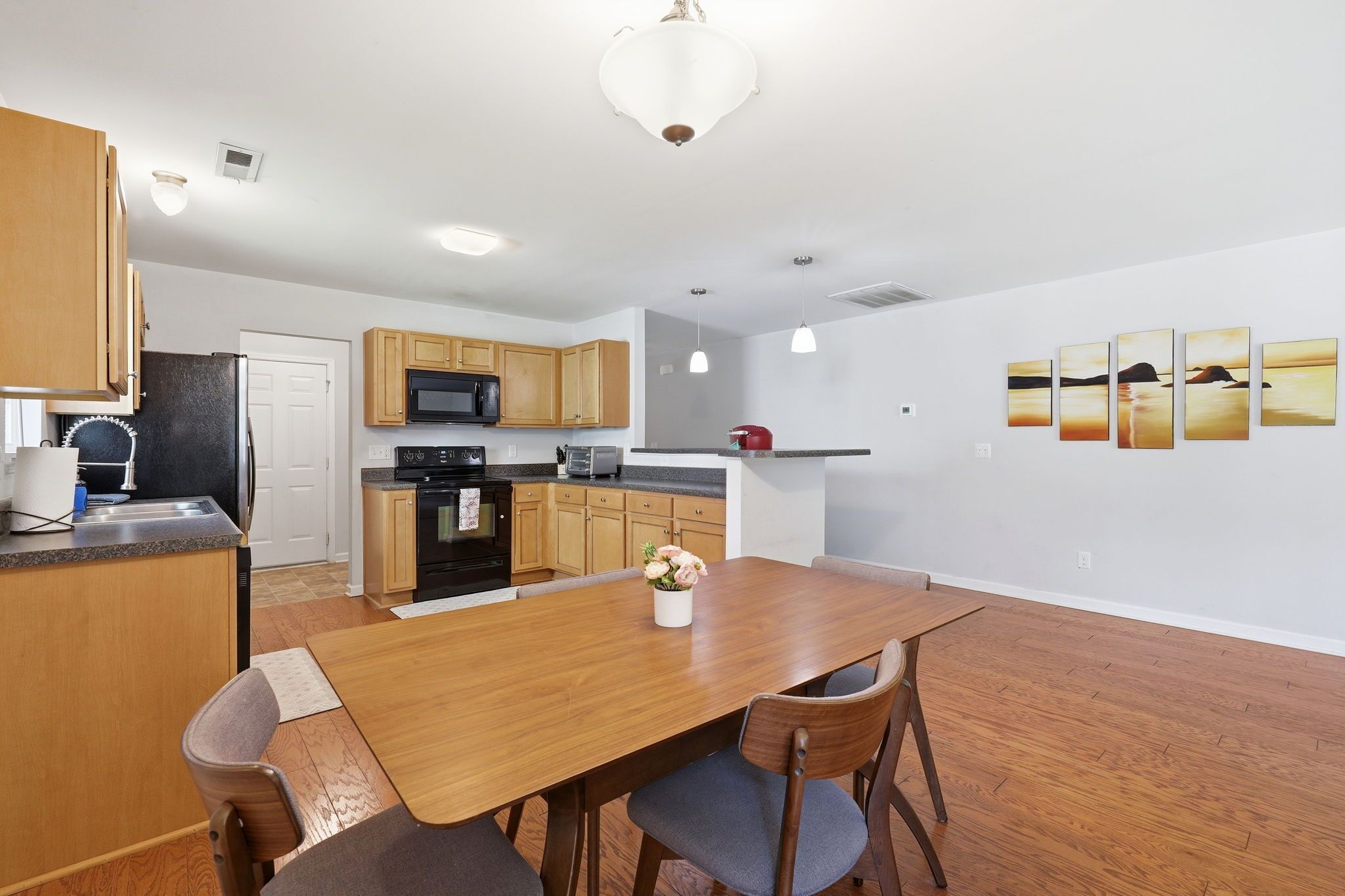 A modern kitchen with wooden cabinets, a dining table, and a refrigerator.