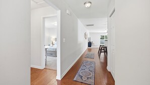 A hallway with wooden flooring, white walls, and a door leading to a bedroom. - Private home along New River NC (Sneads Ferry)