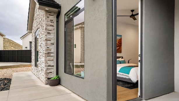 A modern bedroom with a bed, a ceiling fan, and a view of the outside.