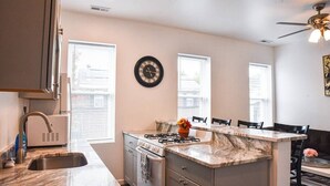 A kitchen with a marble countertop, a stove, a sink, and a clock on the wall. - Beautiful Pittsburgh home-walkable area w parking (Pittsburgh)