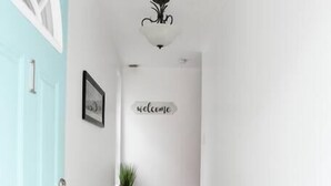 A hallway with a light blue door, a welcome sign, a small plant, and a wooden floor. - Beautiful Pittsburgh home-walkable area w parking (Pittsburgh)