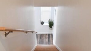 A staircase with wooden steps and a handrail, leading to a landing with a potted plant. - Beautiful Pittsburgh home-walkable area w parking (Pittsburgh)