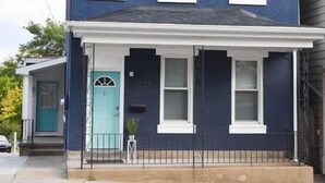 Ein zweistöckiges Haus mit blauer Fassade, weißer Verzierung und einer türkisblauen Haustür.