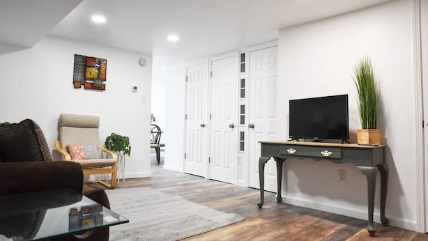Een woonkamer met een bank, een salontafel, een tv op een standaard en een plant.
