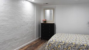 Een slaapkamer met een bed, een dressoir, een spiegel en een raam.