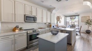 A modern kitchen with white cabinets, stainless steel appliances, and a central island.