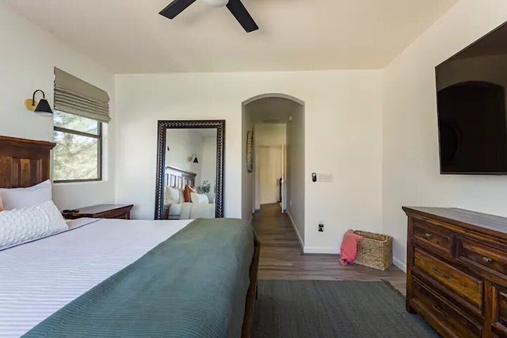 Une chambre à coucher avec un lit, une commode, un miroir et un ventilateur de plafond.