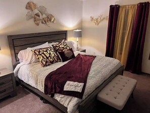 Relax in a serene bedroom with a large bed, bedside table, and decorative wall piece.