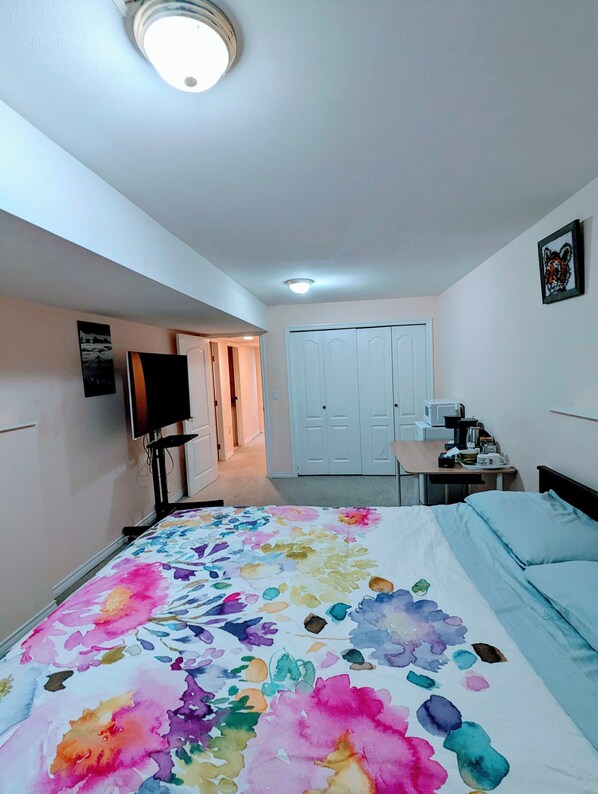 A hotel room with a bed, a desk, a chair, a TV, and a door. - Quiet and big room in Coquitlam (Coquitlam)