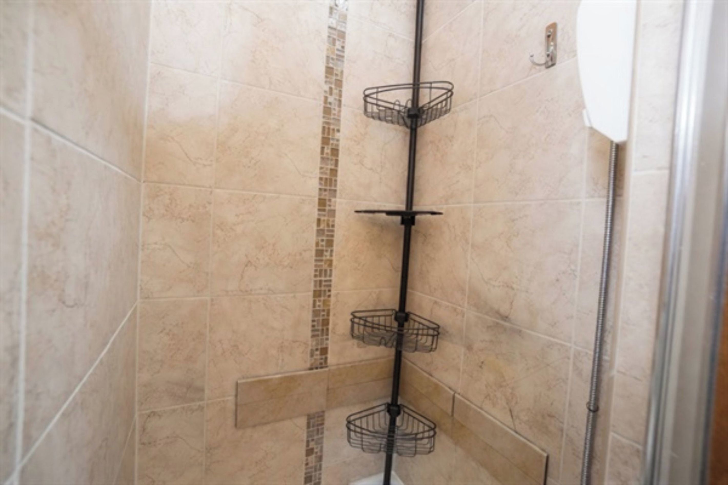 A shower with a vertical metal rack and a tiled wall.