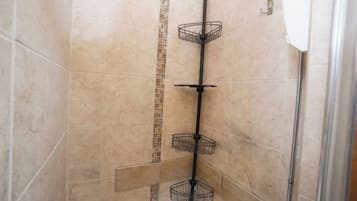 A shower with a vertical metal rack and a tiled wall.