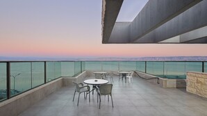 A terrace with a table and chairs, a view of the sea, and a stone wall. - luxury suites (Tiberias)