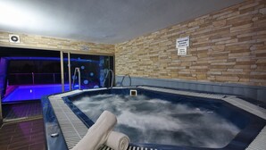 A hot tub with steam, a towel, and a stone wall. - luxury suites (Tiberias)