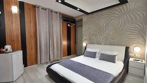 A modern bedroom with a large bed, a bedside table, a nightstand, a built-in wardrobe, and a small kitchenette. - luxury suites (Tiberias)