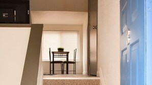 Escada com carpete bege que leva a uma sala de jantar com mesa e cadeiras.