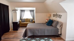 Quarto com cama, sofá, luminária e um objeto decorativo na parede.