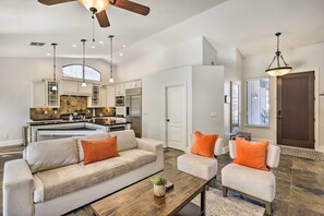 A spacious living room with a large sofa, two armchairs, and a coffee table. A kitchen with modern appliances is visible in the background. - Tee Off, Relax Poolside! Family Home in Scottsdale (Scottsdale)