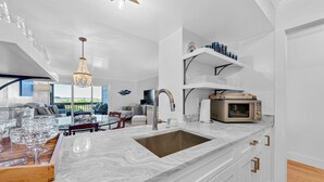 Una cucina moderna con un piano di lavoro in marmo, lavello in acciaio inossidabile e forno a microonde integrato.
