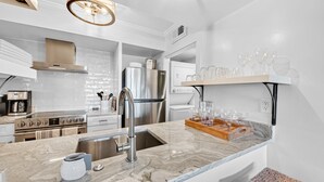 Una cucina moderna con un piano di lavoro in marmo, elettrodomestici in acciaio inossidabile e un vassoio di legno.