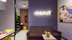 A modern interior with a brown sofa, a small table with a fruit bowl, a neon sign, and a colorful artwork. - Three flats close to Vatican - Prati (roma)