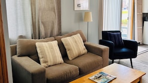 Ein Wohnzimmer mit einer Couch, einem Couchtisch, einem Sessel und einer Lampe.