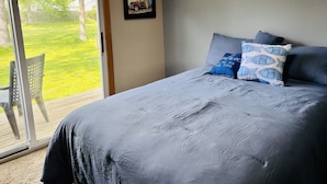 Ein Schlafzimmer mit einem großen Bett, einer Schiebetür zu einer Terrasse und einem gerahmten Bild an der Wand.