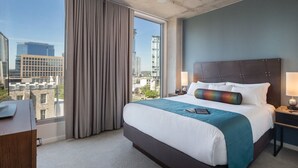 A hotel room with a large bed, a desk, and a view of the cityscape. - 1BD/Austin - Rooftop Pool & Firepit, BBQ! (Austin)