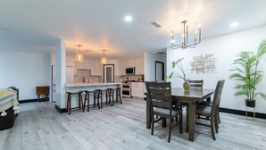 A modern kitchen with white cabinets, a central island with stools, and pendant lighting.