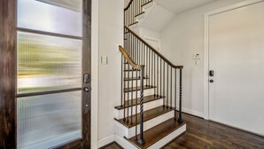 A staircase with wooden steps and black railings, leading to a white door. - Stoic Sanctuary @ East Downtown (Houston)