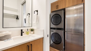 Una cocina moderna con electrodomésticos de acero inoxidable, armarios de madera y encimera blanca.