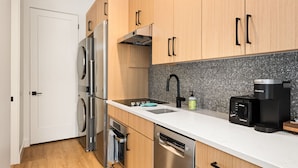 Una cocina moderna con electrodomésticos de acero inoxidable, cafetera y lavavajillas.