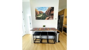 Una cocina moderna con una mesa de madera, taburetes negros y un cubo de basura de acero inoxidable.