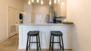A kitchen with a white countertop, two stools, hanging light fixtures, and stainless steel appliances. - ✪ Best Apartment in Westport Kansas City ✪ (Kansas City)