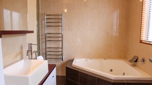 Un baño moderno con una bañera grande, un tocador con espejo y un perchero para toallas.