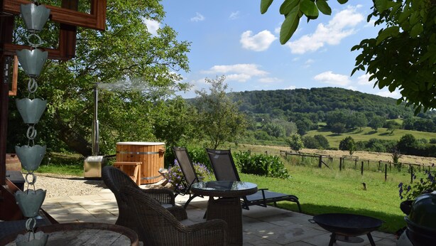 A patio with wicker furniture, a grill, and a view of a vineyard. - Shephards Hut With Hot Tub in the Cotswolds (Stroud)