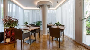 A modern dining area with wooden tables and chairs, large windows with sheer curtains, and a central white pillar. - 3015 B&B Luxury Carra City - Camera Matrimoniale (Gallipoli)