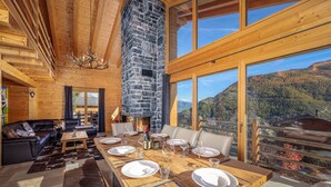 A wooden interior with a stone fireplace, a dining area set for six, and a sofa. - Chalet Amerhone - Luxury Chalet With Jacuzzi (Riddes)