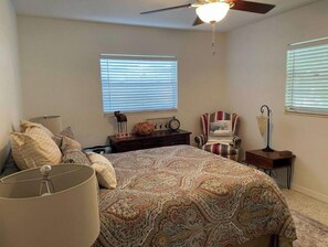 Relax in this cozy space with a large bed, ceiling fan, and comfortable seating area.