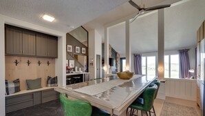 Una cocina amplia con una isla grande, sillas verdes y un ventilador de techo.