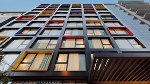 Un edificio moderno con una fachada de ventanas enrejadas, algunas con marcos de colores.