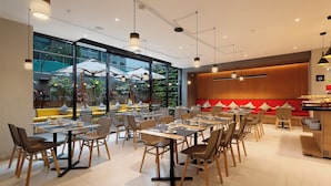 Un restaurante moderno con varias mesas y sillas, amplias ventanas y un ambiente luminoso.