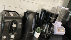Una encimera de cocina con un tostador, una cafetera, una licuadora y una suculenta en maceta.