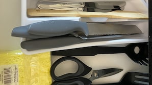 Un cajón con varios utensilios de cocina, incluyendo tenedores, cucharas, un cuchillo y un par de tijeras.
