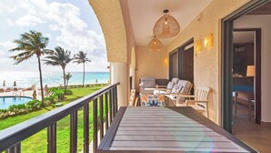 Ein Balkon mit Blick auf das Meer, einen Pool und Palmen.