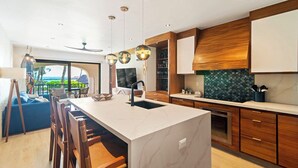 Eine moderne Küche mit einer großen Kochinsel, Holzschränken und Pendelleuchten.