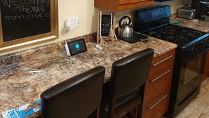 A kitchen with wooden cabinets, a granite countertop, a stove, and a chalkboard with a welcome message. - Colorful 4-bedroom house-Vet owned-NAVAL Academy (Waukegan)